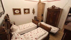Een slaapkamer met twee houten bedden, een houten garderobe en een hoge, decoratieve kast.