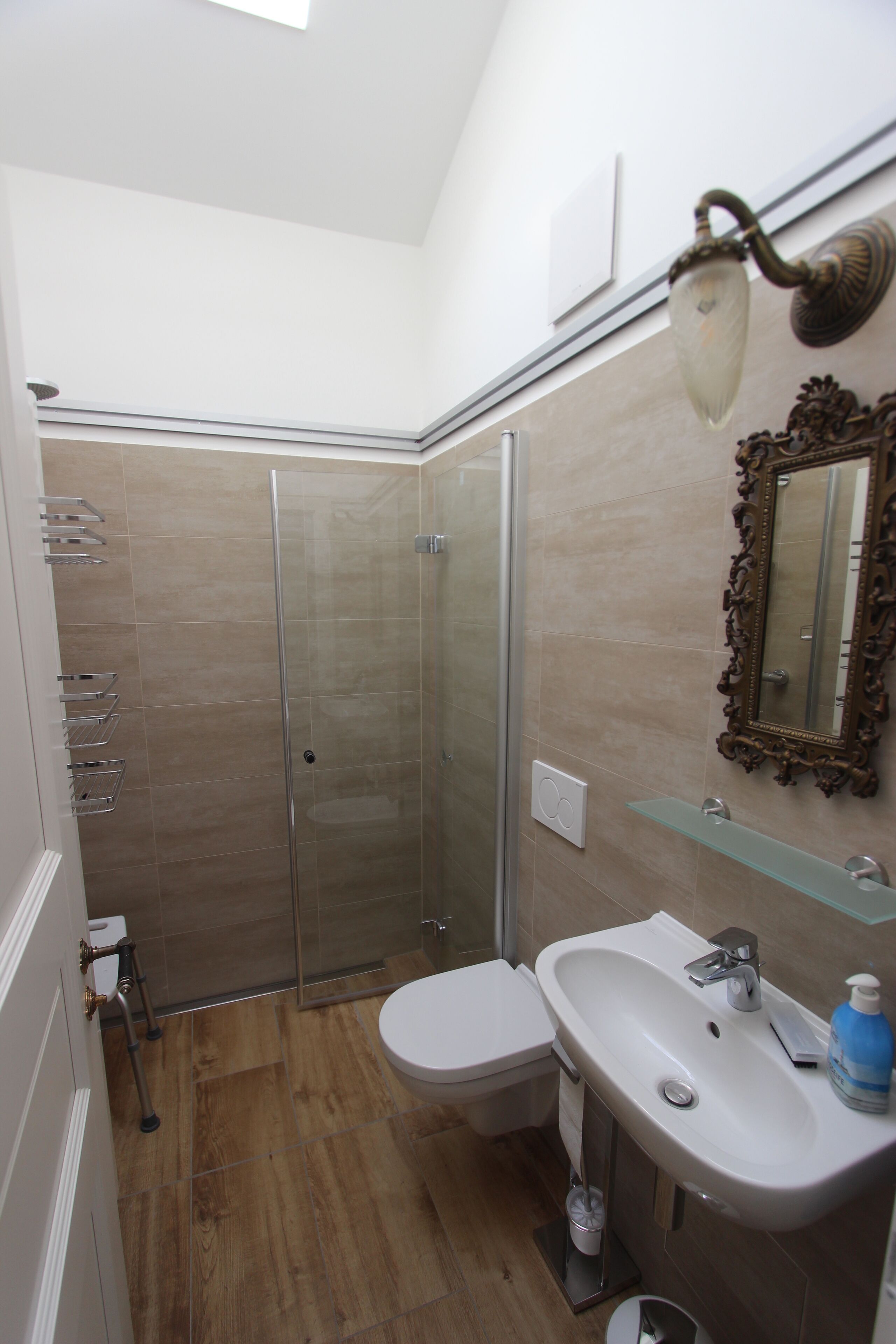 Een moderne badkamer met een douchecabine van glas, een wit toilet, een wastafel met spiegel en een glazen plank.