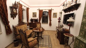 Een klassieke kamer met houten vloer, een bank, een tafel, een spiegel en een kast.