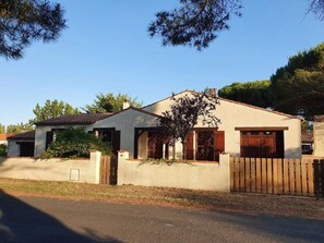 A single-story house with a sloped roof, a wooden fence, and a small garden area.