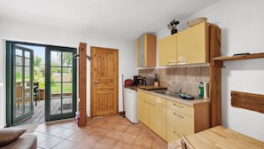 Een compacte keuken met houten kastjes, een inbouwoven en een klein eethoekje met een tafel en stoelen.