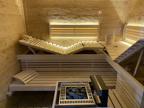 Een sauna met houten banken en een stenen warmtebron.