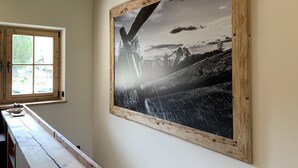 Ein Zimmer mit einem großen, gerahmten Schwarz-Weiß-Foto von einer Berglandschaft, einem Holster und einer hölzernen Bank.