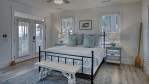 A bedroom with a bed, bedside tables, a bench, and a ceiling fan. - Sweet Gum Cottage Oceanfront 5BDR with Golf Cart (Daufuskie Island)