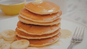 A stack of pancakes with syrup and banana slices on a plate. - Ambassador Resort (Shengjin)