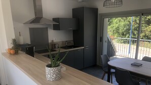 Een moderne keuken met donkere kastjes, een houten aanrechtblad en een eethoek met een tafel en stoelen.