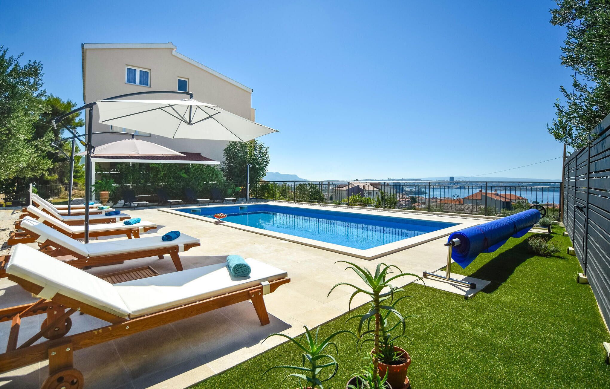 Une piscine avec des chaises longues, un espace abrité et une vue sur la mer.