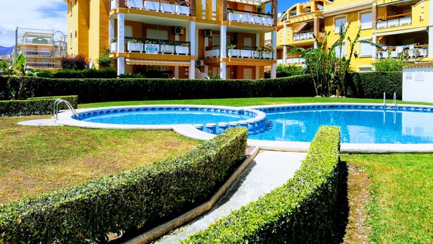 Et hotel med swimmingpool, flere balkoner og en velholdt have.