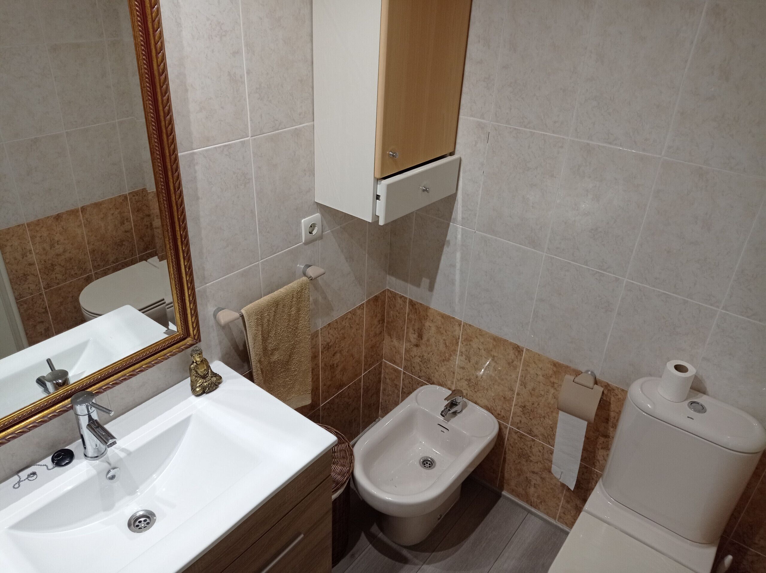 Een badkamer met een wit wastafel, een bidet, een toilet en een spiegel met gouden lijst.
