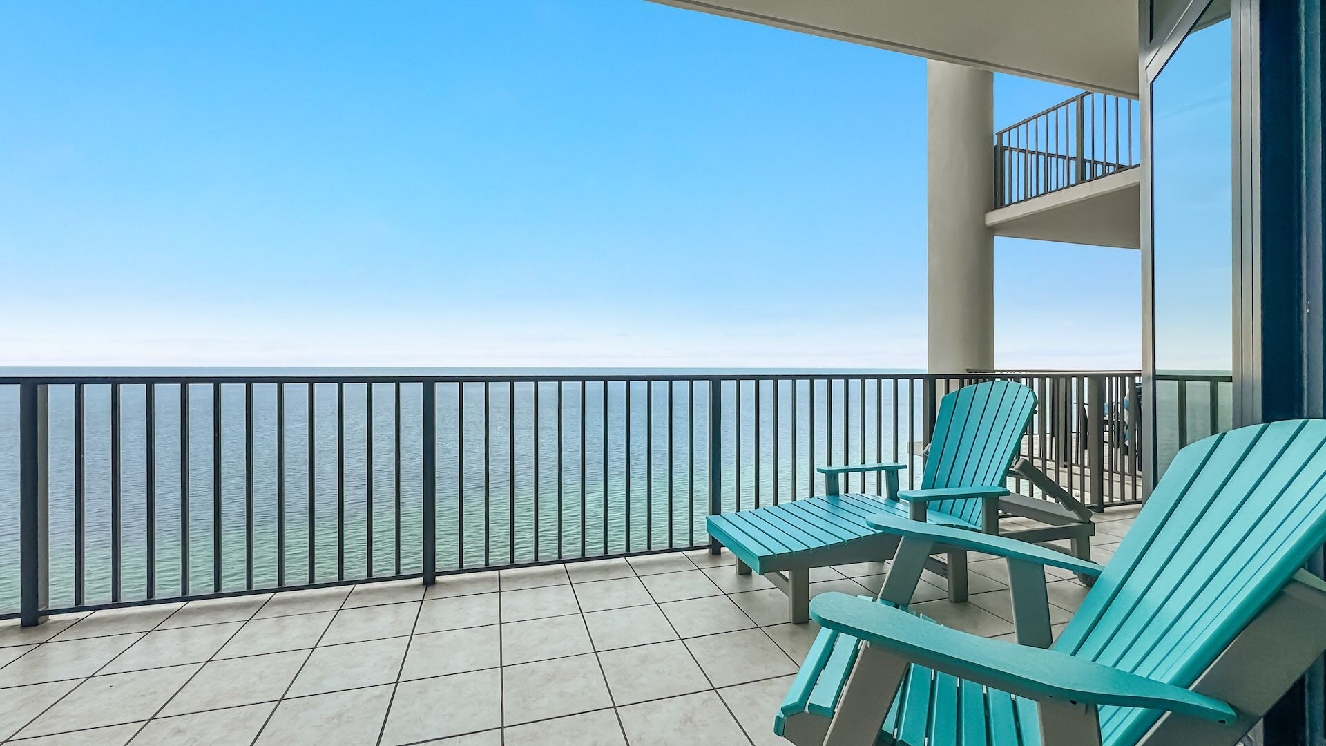 A balcony with two chairs and a view of the sea.