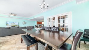 A spacious dining area with a long wooden table, leather chairs, and a chandelier. - New to the Rental Market, New Owner!!  Beachfront!! (Orange Beach)