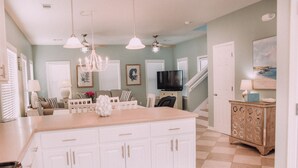A spacious kitchen with white cabinetry, a large island, and a dining area with striped chairs.