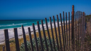 A beach with a wooden fence and barbed wire, leading to the ocean.