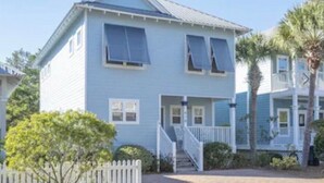 A two-story house with a front porch, a staircase, and a picket fence.
