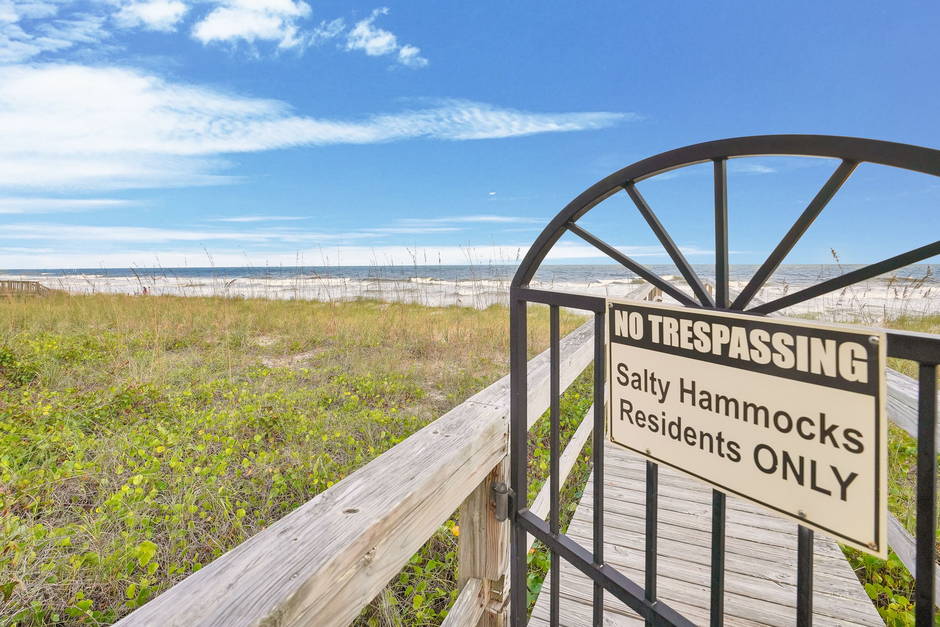 Ein begrenzter Zugang zu einem Strandbereich mit einem Schild, das FKK Silhouetten für Bewohner von Salty Hammocks verbietet.