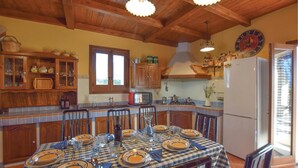 A kitchen with wooden cabinets, a dining table set for four, and a refrigerator. - Beautiful home in Giarratana (Giarratana)