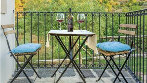 A balcony with two chairs and a table, each with a cushion, and two wine glasses and a bottle of wine. - Beautiful home in Giarratana (Giarratana)