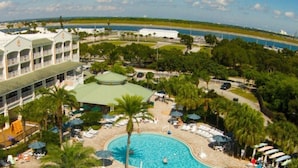 A hotel with multiple balconies, a swimming pool, and a view of the ocean.