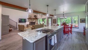 A spacious kitchen with a large island, pendant lighting, and a view to the outdoors. - LD 727 Down River Haus (New Braunfels)