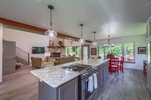 A spacious kitchen with a large island, pendant lighting, and a view to the outdoors.