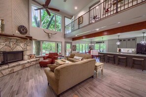A spacious living area with a fireplace, a sofa, a dining area, and a kitchen.