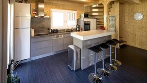 Cozinha moderna com eletrodomésticos de aço inoxidável, uma ilha central com banquetas e paredes de madeira.
