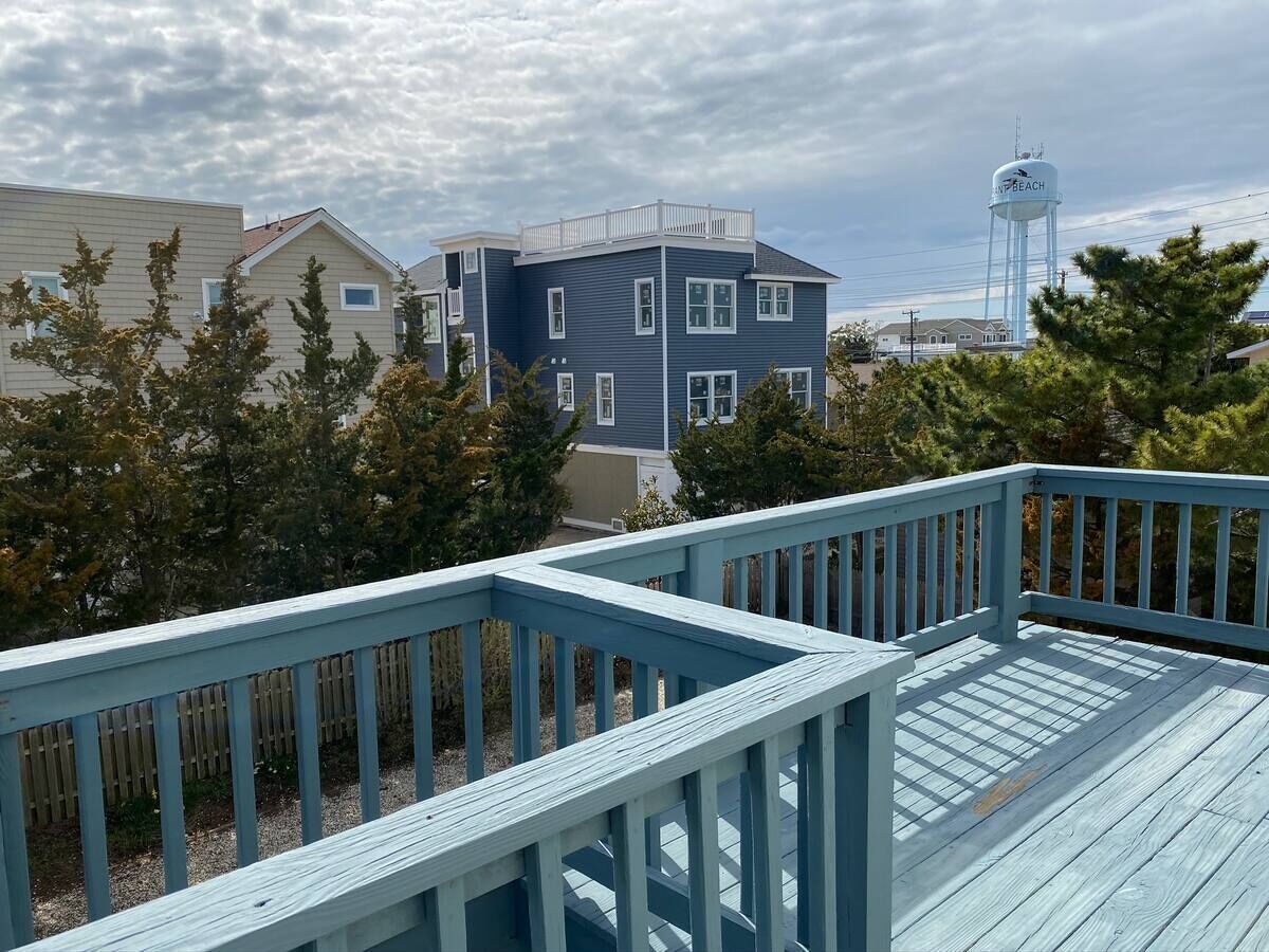 A wooden deck with railings, a water tower in the background, and a building with a blue facade.