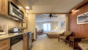 Une chambre d’hôtel équipée d’une kitchenette, d’un lit, d’un coin salon et d’un ventilateur de plafond.
