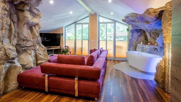 Una sala de estar moderna con un sofá rojo, una bañera blanca y un ventanal grande.