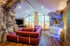 Una sala de estar moderna con un sofá rojo, una bañera blanca y un ventanal grande.