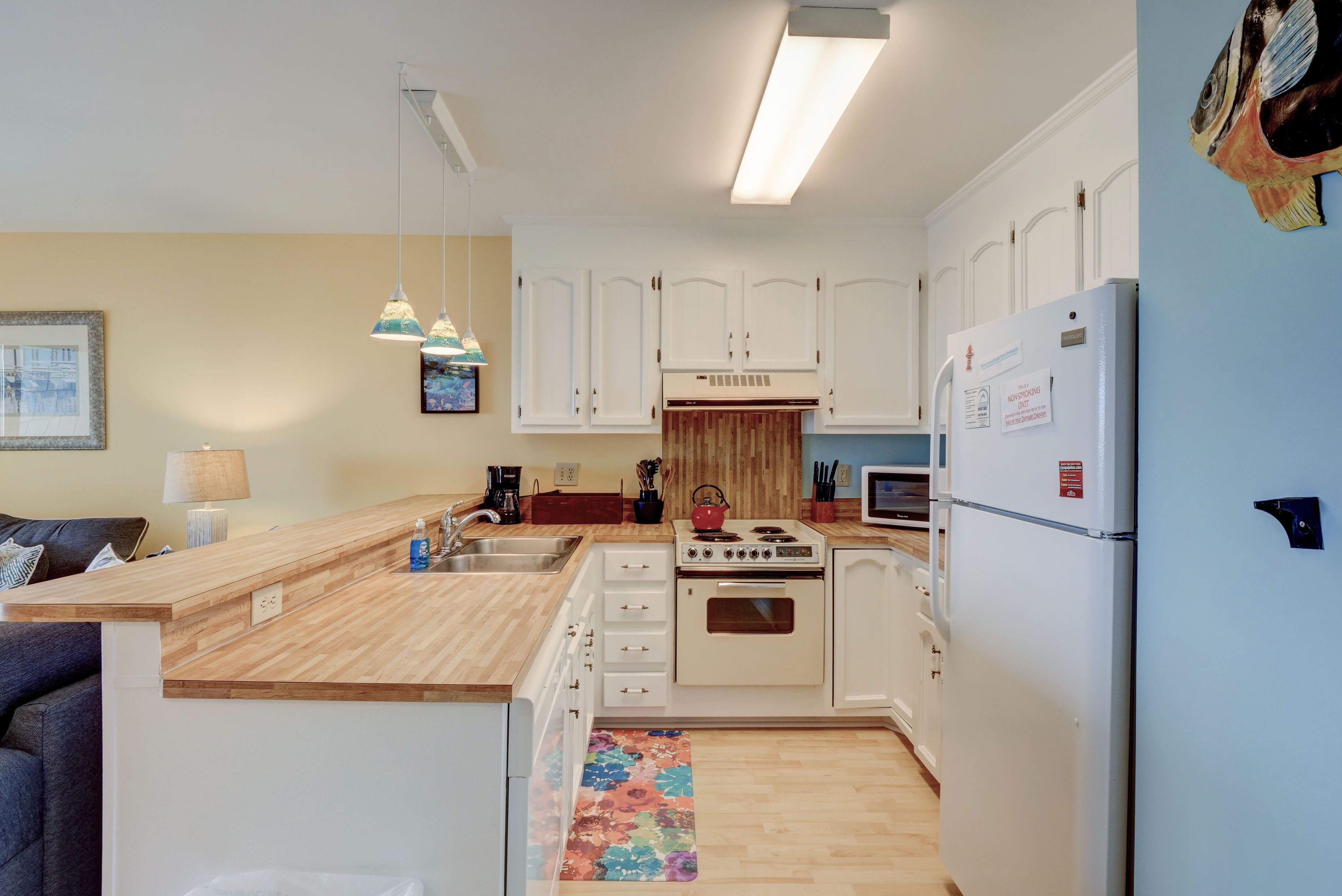 A compact kitchen with white cabinets, a wooden countertop, a stove, and a refrigerator.