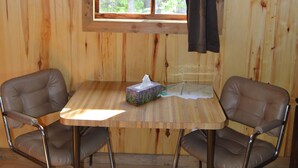 A wooden cabin room with a window, two leather chairs, a table, and a tissue box. - Last minute Plan to Glacier Guest Cabin Sauna  (Essex)