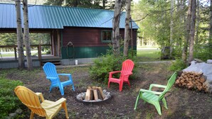 A cabin with a porch, surrounded by trees and outdoor seating chairs. - Last minute Plan to Glacier Guest Cabin Sauna  (Essex)