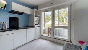 Una cocina moderna con gabinetes blancos, encimera negra y microondas integrado.