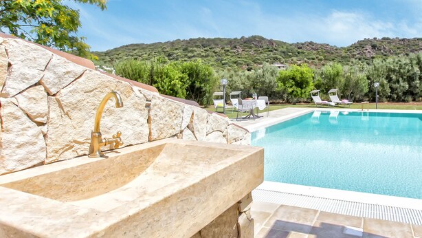 A stone sink with a gold faucet, a pool with clear blue water, and a view of green hills in the background. - Luxury Villa Laura - new infinity pool, relax and privacy for your holidays (Alghero)