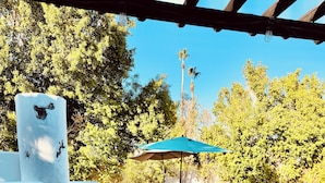 A patio area with a white outdoor oven, lounge chairs, a pool, and a blue umbrella. - Palm Springs Private Retreat Pool & Mountain Views (Palm Springs)