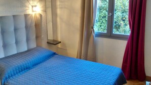 A bedroom with a bed, a bedside table, a hanging light, and a window with curtains. - VILLA 200 M from the BEACH (Sainte-Marie-la-Mer)