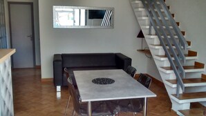 A modern living space with a dining table, black sofa, and a staircase. - VILLA 200 M from the BEACH (Sainte-Marie-la-Mer)
