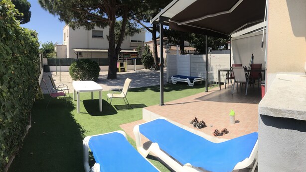 A patio area with two blue lounge chairs, a white table, and a covered seating area. - VILLA 200 M from the BEACH (Sainte-Marie-la-Mer)
