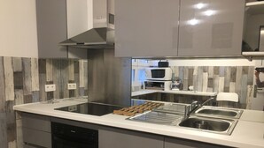 A modern kitchen with a central island, stainless steel appliances, and a wooden backsplash.