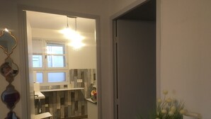 A modern kitchen with white cabinets, a tiled floor, and a hanging light fixture.