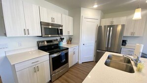 Una cocina moderna con armarios blancos, electrodomésticos de acero inoxidable, un horno negro y un lavamanos grande.