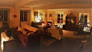 Ein gemütliches Wohnzimmer mit Kamin, Esstisch und Weihnachtstannenbaum.