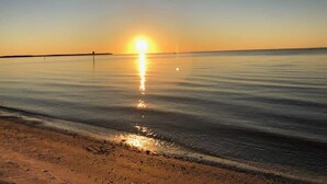 Une plage paisible au coucher du soleil, sous un ciel dégagé.