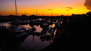 Un port de plaisance au crépuscule, avec des bateaux amarrés et une eau calme qui reflète le ciel.