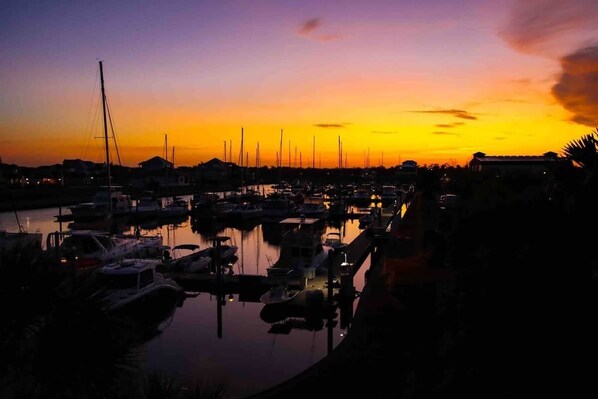 Un puerto deportivo al atardecer con barcos amarrados y agua tranquila que refleja el cielo.