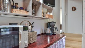 Una cucina con forno a microonde, macchina del caffè e ripiani con utensili da cucina.