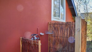 Un edificio rosso con recinzione in legno, una finestra e un tubo da giardino.