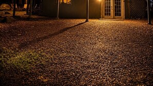 Ein zweistöckiges Haus mit überdachter Terrasse, Lichterketten und einer Holzterrasse.