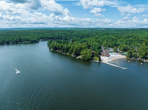 An aerial view of a lakeside resort with a dock, a swimming area, and dense forested areas. - Lake Life Chalet  Huge Deck, Arcade & Fireplace (Hamlin)